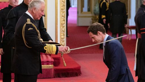 photo of King Charles knighting someone, sword upon their shoulder near their neck